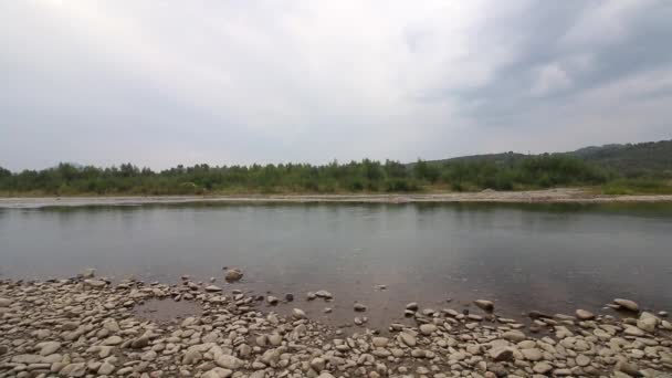 Cours d'eau d'une rivière de montagne. Il coule calmement dans la vallée. Pierres visibles sur les berges. Sur l'horizon montagneux avec des forêts .