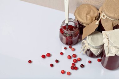 Ev yapımı reçeller, kavanozlarda kızılcık reçeli. Bir açık olabilir, bir çay kaşığı vardır. Birkaç çilek yüzeye serpilir.