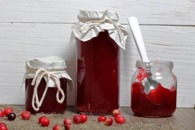 Ev yapımı reçeller, kavanozlarda kızılcık reçeli. Bir açık olabilir, bir çay kaşığı vardır. Birkaç çilek yüzeye serpilir.