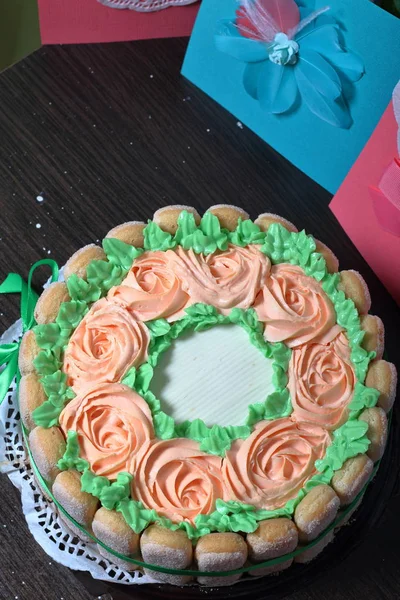 Pastel de esponja con queso crema, decorado con galletas Savoiardi. En el lateral, envuelto en una cinta atada a un lazo. Cerca de una tarjeta de felicitación . — Foto de Stock