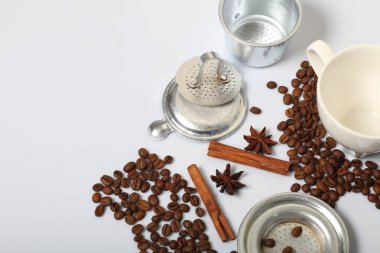 Kahve çekirdekleri, tarçın çubukları, baharat ve anason. Beyaz bir bardağın yanında. Beyaz arka planda. Dünya Kahve Günü.