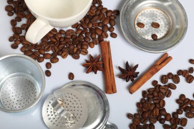 Kahve çekirdekleri, tarçın çubukları, baharat ve anason. Beyaz bir bardağın yanında. Beyaz arka planda. Dünya Kahve Günü.
