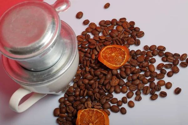 Una taza de café con una cafetera vietnamita. Cerca en la superficie de la mesa hay granos de café y rodajas de naranjas secas. Día Mundial del Café . — Foto de Stock
