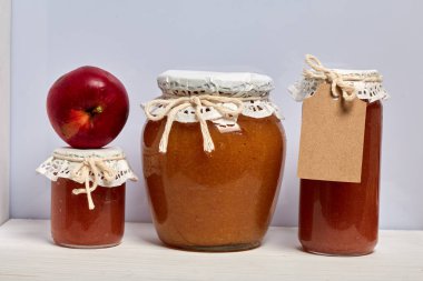 Ev yapımı mevsimlik preparatlar. Elma reçeli güzel paketlenmiş kavanoz. Kağıtla kaplanmış ve bir kordonla bağlanmış. Yakınlarda taze elmalar var..