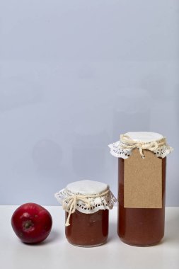 Ev yapımı mevsimlik preparatlar. Elma reçeli güzel paketlenmiş kavanoz. Kağıtla kaplanmış ve bir kordonla bağlanmış. Yakınlarda taze elmalar var..