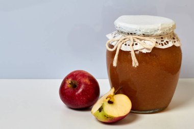 Ev yapımı mevsimlik preparatlar. Elma reçeli güzel paketlenmiş kavanoz. Kağıtla kaplanmış ve bir kordonla bağlanmış. Yakınlarda taze elmalar var..