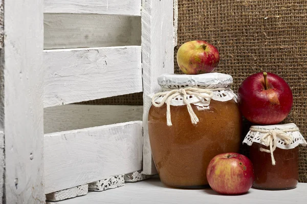 Домашние сезонные препараты. Красиво упакованные банки яблочного варенья. Покрытый бумагой и завязанный шнуром. Рядом свежие яблоки. . — стоковое фото