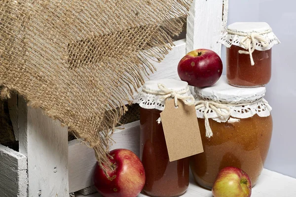 Ev yapımı mevsimlik preparatlar. Elma reçeli güzel paketlenmiş kavanoz. Kağıtla kaplanmış ve bir kordonla bağlanmış. Yakınlarda taze elmalar var.. — Stok fotoğraf