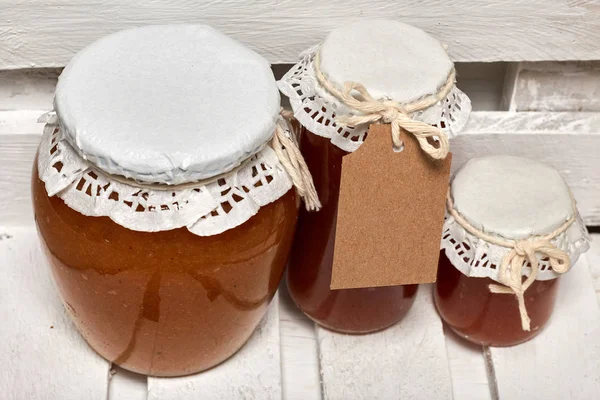 Preparaciones caseras de temporada. Jarras de mermelada de manzana bellamente empaquetadas. Cubierto con papel y atado con un cordón . — Foto de Stock