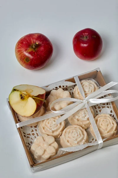 Apple puree marshmallows in a gift box. Tied with a ribbon tied to a bow. Nearby are fresh apples.