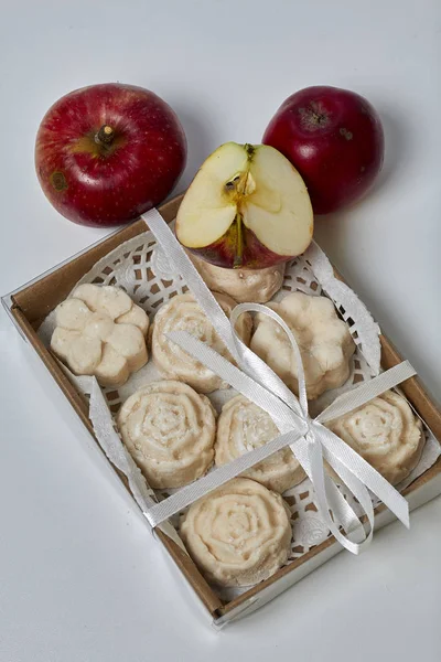 Apple puree marshmallows in a gift box. Tied with a ribbon tied to a bow. Nearby are fresh apples.