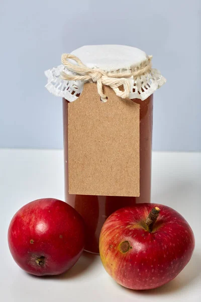 Preparações sazonais caseiras. Belamente embalados jarros de engarrafamento de maçã. Coberto com papel e amarrado com um cordão. Perto estão maçãs frescas . — Fotografia de Stock