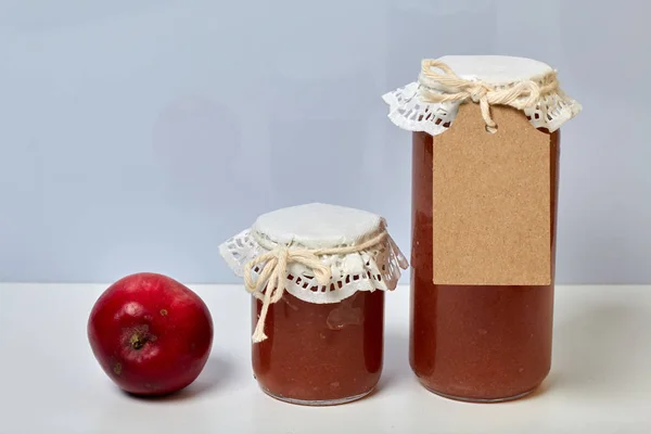 Préparations saisonnières maison. Bocaux de confiture de pommes magnifiquement emballés. Recouvert de papier et attaché avec un cordon. A proximité se trouvent des pommes fraîches . — Photo