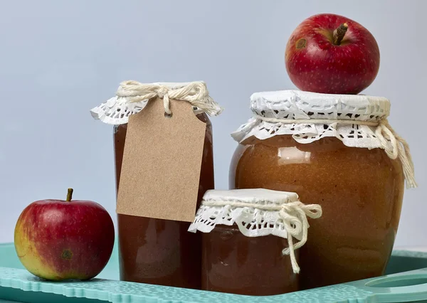 Ev yapımı mevsimlik preparatlar. Elma reçeli güzel paketlenmiş kavanoz. Kağıtla kaplanmış ve bir kordonla bağlanmış. Yakınlarda taze elmalar var.. — Stok fotoğraf