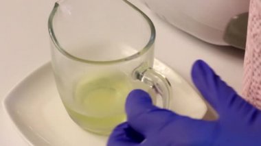 Bir kadın reçelli konteynıra yumurta beyazı ekler. Marşmelov hazırlamak için. Masanın yanında marşmelov yapmak için diğer malzemeler ve araçlar var..