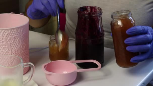 女人把果酱放在一个测量勺子里 用来准备棉花糖的 桌子旁边是制作棉花糖的其他材料和工具 — 图库视频影像