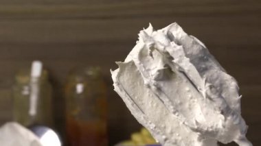 Bir kadın çırpıcının çırpıcısını lokumdan temizler. Kaşıkla çıkarıp bir kabın içine koyuyor..