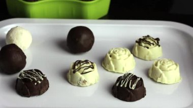 Lastik eldivenli bir adam tepsiye şeker koyar. Beyaz ve siyah çikolatalı jöleli şekerler. Uluslararası Şeker Günü.