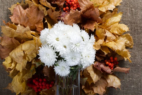 Autumn still life. Wreath of autumn leaves with mountain ash. Nearby is a bouquet of white chrysanthemums. — Stock Photo, Image