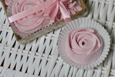 Havadan gelen vişneli şekerlemeler. Şeffaf kapaklı bir hediye kutusunda. Marşmelovların yanında ambalajsız. Hasır asmaların arka planına karşı.