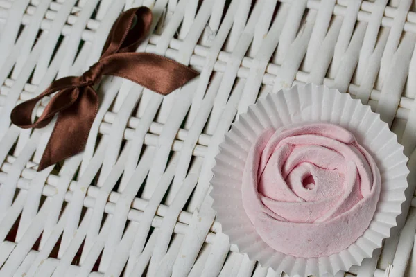 Повітряно-рожевий вишневий зефір. У вигляді троянди. На тлі плетених лоз . — стокове фото