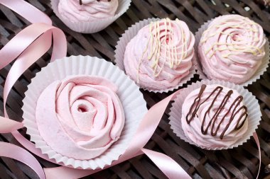 Havadan gelen vişneli şekerlemeler. Bazıları gül şeklinde, diğeri çikolatayla süslenmiş. Hasır asmaların arka planına karşı.