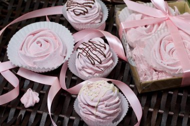 Havadan gelen vişneli şekerlemeler. Şeffaf kapaklı bir hediye kutusunda. Marşmelovların yanında ambalajsız. Hasır asmaların arka planına karşı.