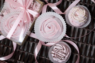 Havadan gelen vişneli şekerlemeler. Şeffaf kapaklı bir hediye kutusunda. Marşmelovların yanında ambalajsız. Hasır asmaların arka planına karşı.