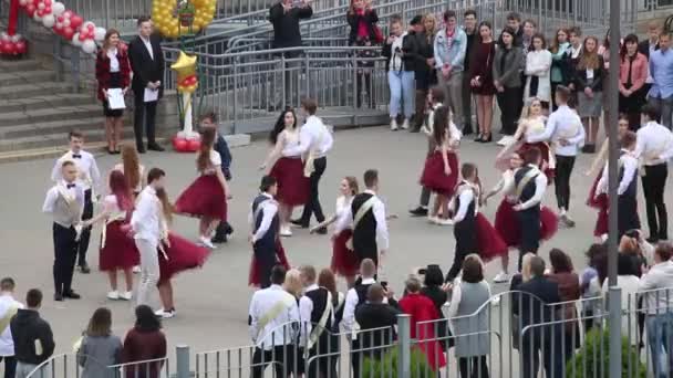 В Беларуси 29 мая 2020 года выпускники школы танцуют вальс. Мальчики и девочки на последнем вызове. В окружении гостей — стоковое видео