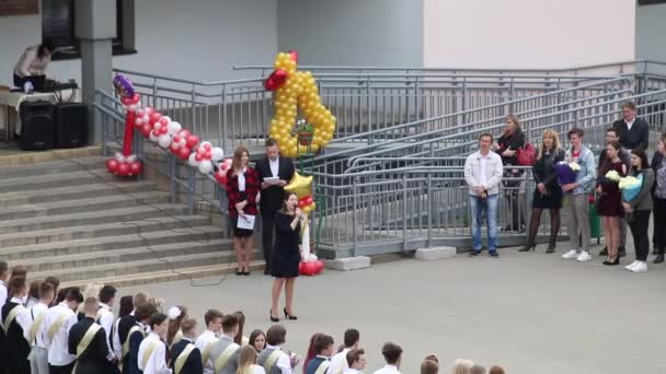 MINSK, BELARUS 29 mei 2020 Laatste oproep op school. Afgestudeerden kijken naar de school. Het meisje zingt een liedje.. — Stockvideo