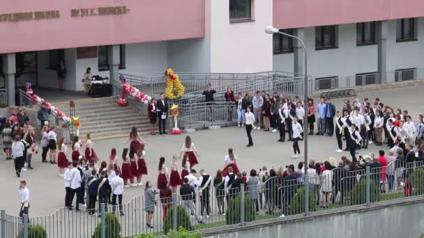 MINSK, BELARUS MAY 29, 2020 Los graduados de la escuela bailan un vals. Chicos y chicas en la última llamada. Rodeado de invitados. La escuela está decorada festivamente . — Vídeo de stock