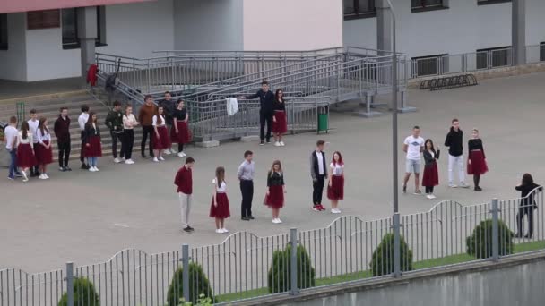 MINSK, BELARUS MAY 29, 2020 Los graduados de la escuela salen en grupo para ensayar un vals escolar. Niños y niñas se preparan para el baile — Vídeo de stock