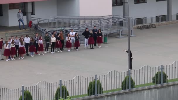 MINSK, BELARUS MAIO 29, 2020 Os graduados da escola estão de pé em um grupo, antes do ensaio da valsa escolar. Meninos e meninas de terno estão de pé em uma fileira . — Vídeo de Stock