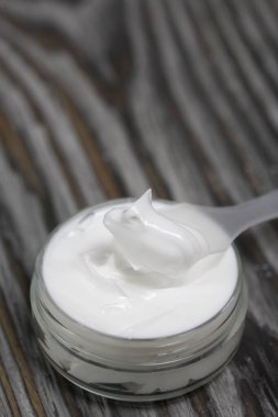 Kremalı plastik şişe. Kürek kemiğinin yanında, üzerinde krem var. Çam ağacının arka planında.