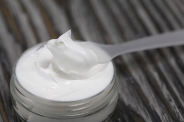 Kremalı plastik şişe. Kürek kemiğinin yanında, üzerinde krem var. Çam ağacının arka planında.