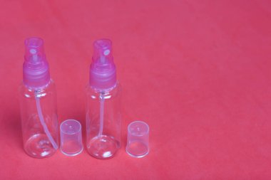 Kozmetik için spreyli plastik şişeler. Mercan renginin arka planına karşı.
