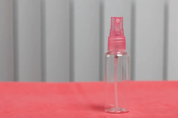 Plastic bottle for cosmetics with a spray. On the surface of coral color.