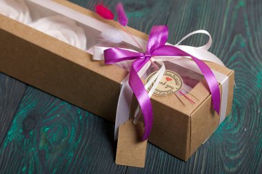 Kağıt ambalajda marşmelov. Kurdelelerle ve kurumuş çiçeklerle süslenmiş. Gül şeklinde bir Zephyr. Boyalı çam tahtalarında.