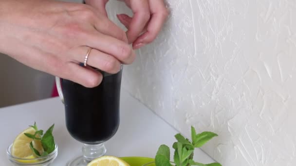 Thé bleu de Thaïlande ou Clitoria triple dans un gobelet en verre. Une femme la décore de chaux et de menthe. Ajoute des morceaux de glace. — Video