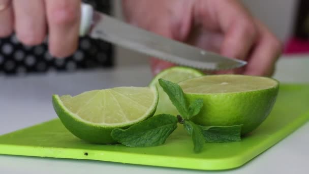 Frau schneidet Limette. Zum Drink hinzufügen. In der Nähe sind Minzblätter. — Stockvideo