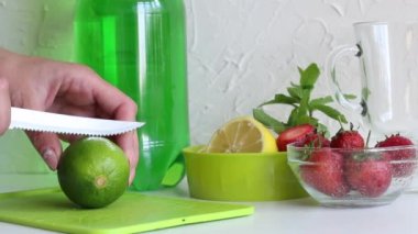 Kadın limon dilimliyor. Yeşil limonata, narenciye ve nane likörü hazırlamak için. Kokteyl için yakın malzemeler..