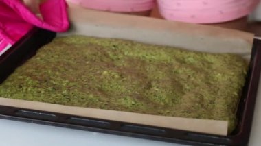 Bir kadın masaya fırında kekle birlikte bir yemek tepsisi koyar. İsviçre rulosu yapma süreci.