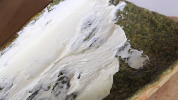Egy nő spenót és menta hozzáadásával keksz tortával keni a tejszínt. A svájci tekercskészítés folyamata. Közelkép.. — Stock videók