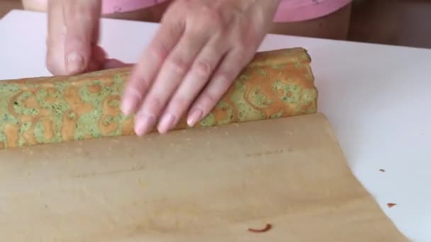 Eine Frau breitet einen Biskuitkuchen aus, der in eine Röhre gerollt wird. Der Prozess der Schweizer Rolle. — Stockvideo