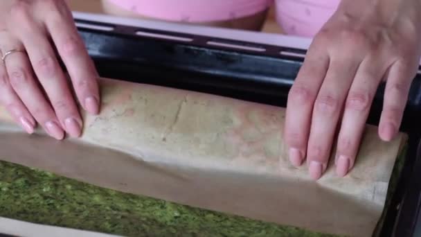 Una mujer hace rodar un bizcocho al horno con espinacas y menta. El proceso de hacer rollo suizo . — Vídeos de Stock