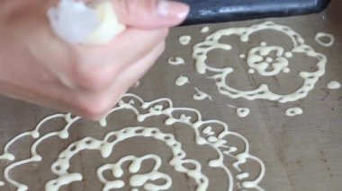 Bir kadın hamur kalıbını bir yemek tepsisine çizer. İsviçre dürümü yapma süreci. Yakın çekim.