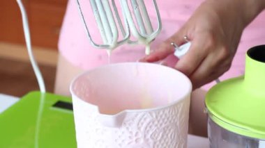 Bir kadın blender 'ın venchiui' sini hamurdan silkeliyor. İsviçre dürümü yapma süreci. Yakın çekim..