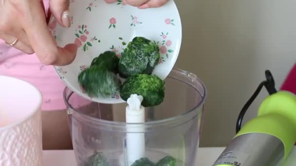 A woman adds frozen spinach to a blender bowl. The process of making Swiss roll. Close-up shot. — Stock Video