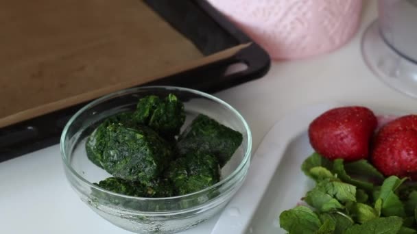 Ingredientes para hacer rollo suizo. Espinacas, menta, fresas y más en la superficie de la mesa . — Vídeo de stock