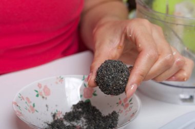 Bir kadın elinde kurutulmuş meyve şekeri tutuyor. Kuru erik, hurma ve hindistan cevizi topları. Bir tutam siyah susam tozuyla.